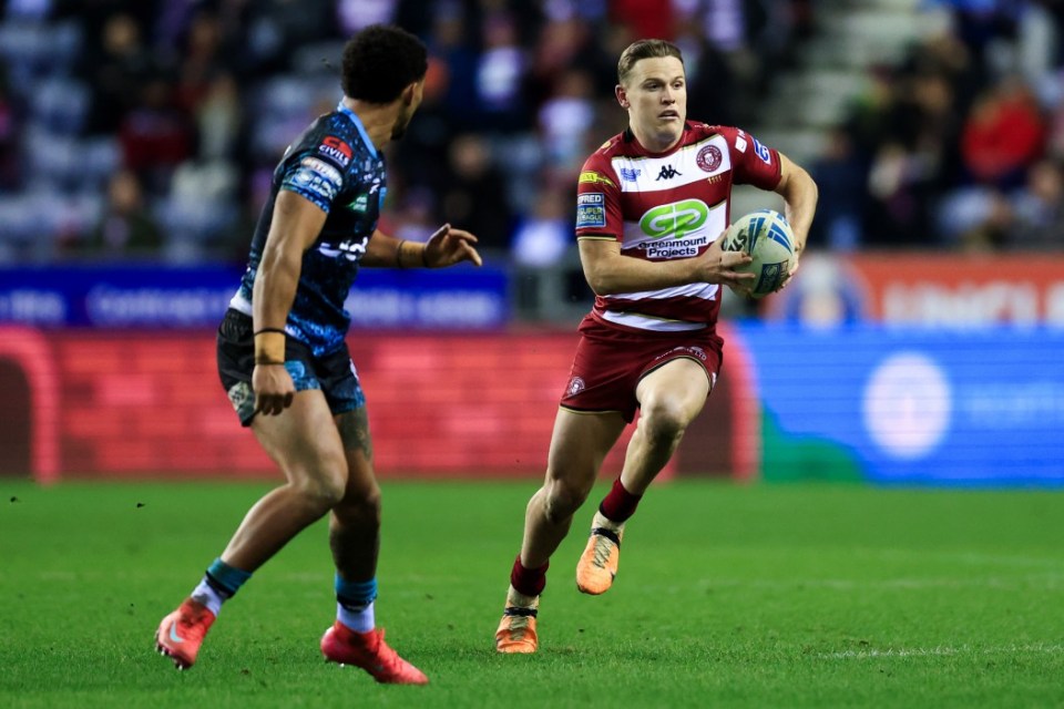 WIGAN, ENGLAND - FEBRUARY 13: Jai Field of Wigan Warriors runs with the ball whilst under pressure from Umyla Hanley of Leigh Leopards during the Betfred Super League match between Wigan Warriors and Leigh Leopards at Brick Community Stadium on February 13, 2025 in Wigan, England. (Photo by Jess Hornby/Getty Images)