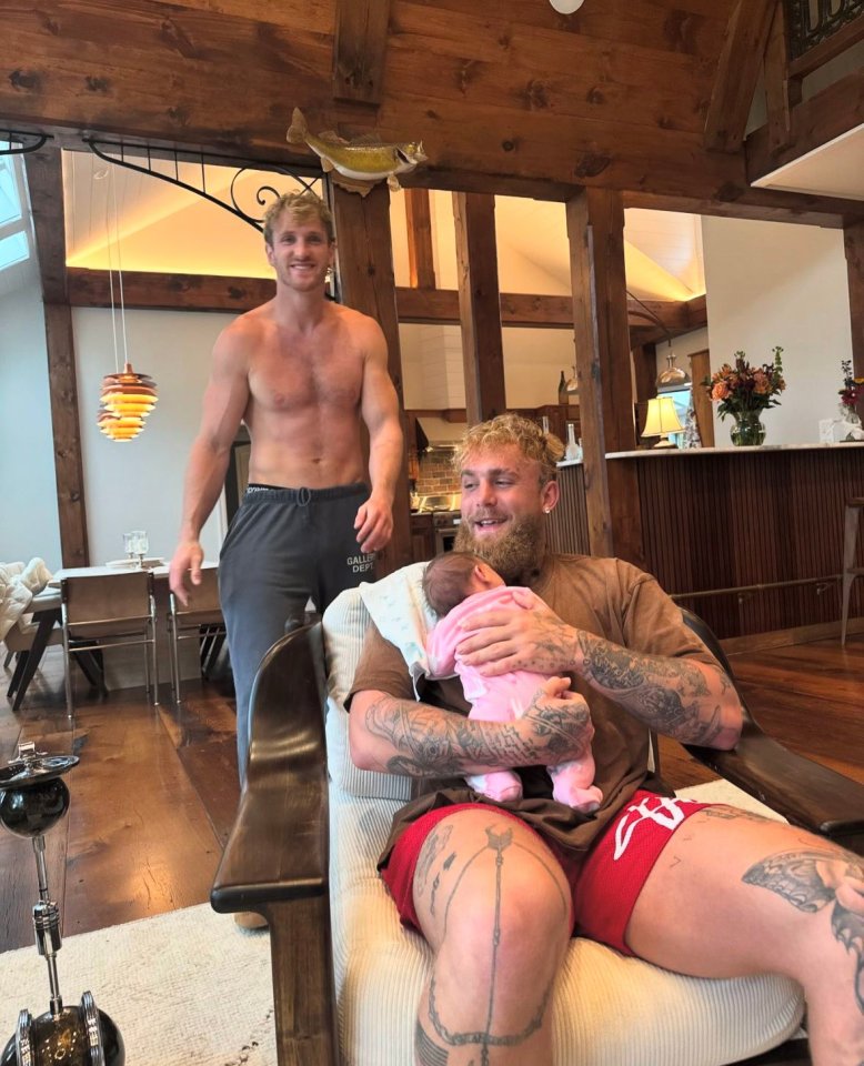 Two shirtless men with one holding a baby.