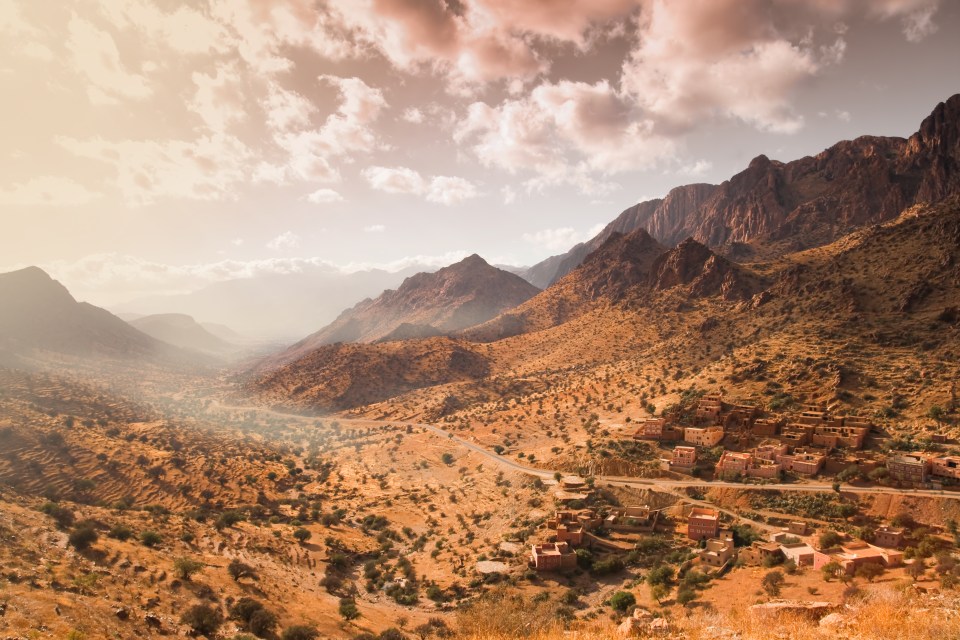 Morocco africa town rural decay dry desert mountains summit peak top landscape fog brown dust clouds travel trip tour route holidays vacations mud construction architecture buildig house some abandoned vegetation horizon Ouarzazate