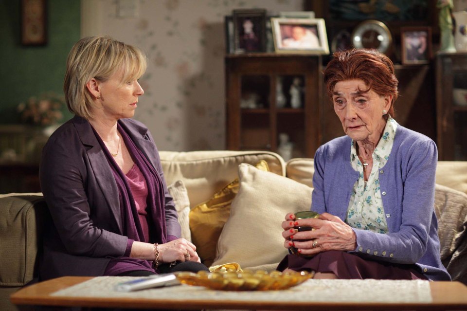 Two women sitting on a couch talking.