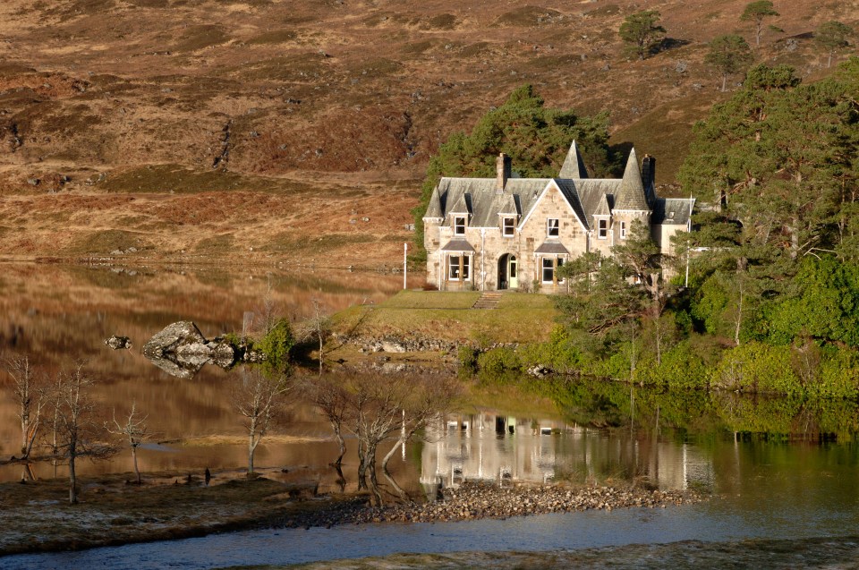 Stone house reflected in a loch.