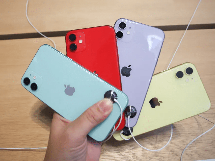 Hand holding several iPhones in different colors.