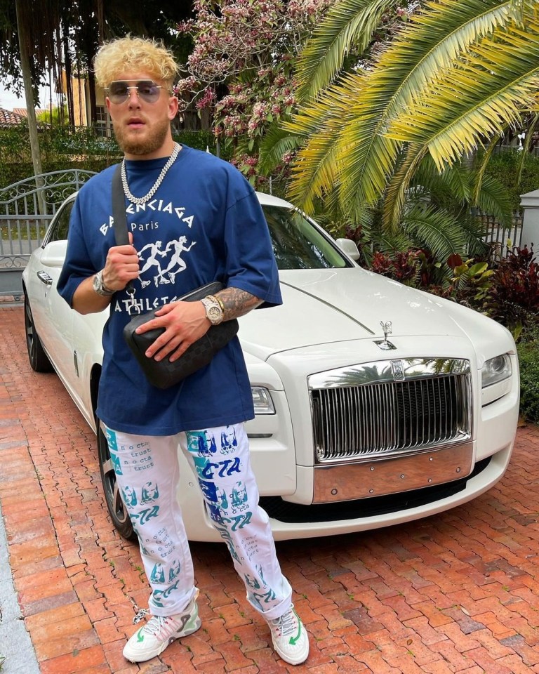 Jake Paul standing next to a white Rolls Royce.