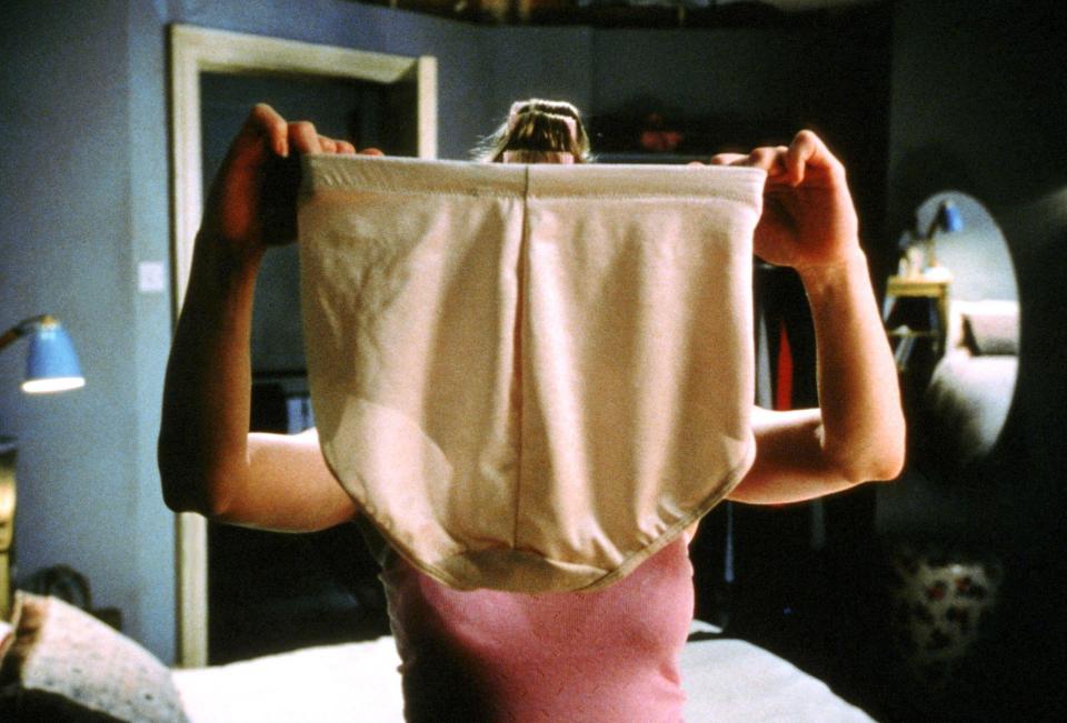 A woman holding a pair of panties in front of her face.