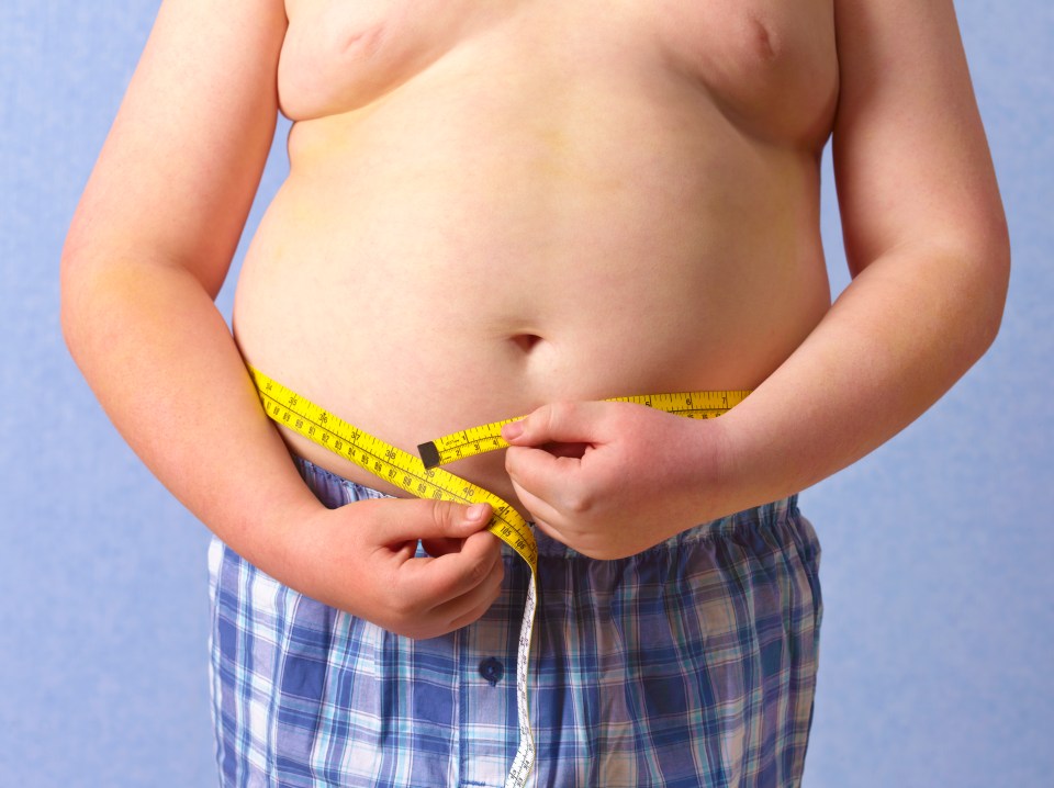 Overweight child measuring waist with tape measure.