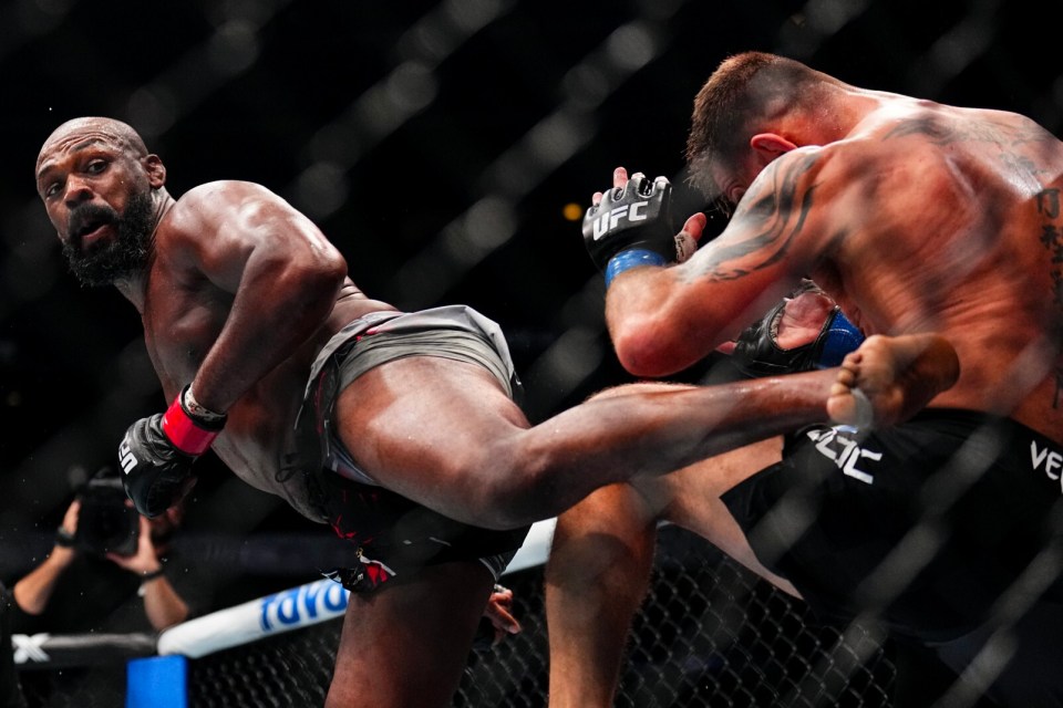 A mixed martial arts fighter delivering a kick to his opponent.