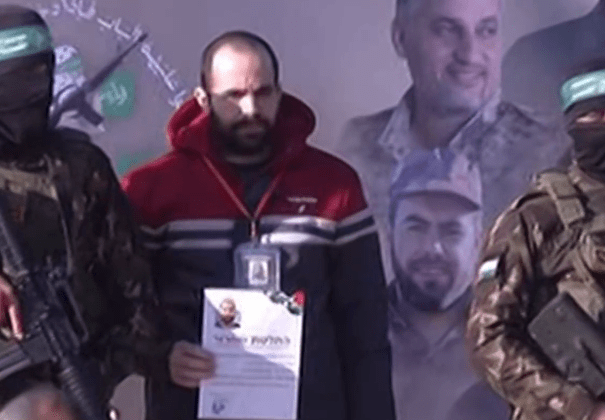 Man holding certificate flanked by armed men.