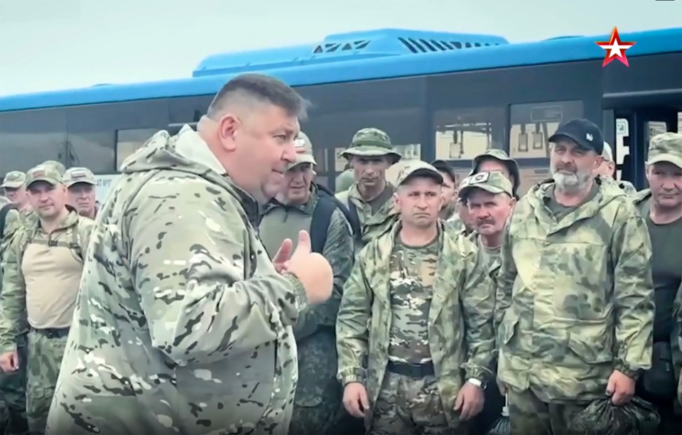 A man in camouflage giving a thumbs up to a group of soldiers.