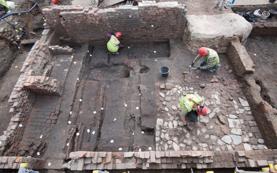 Archaeologists excavating an ancient brick structure.