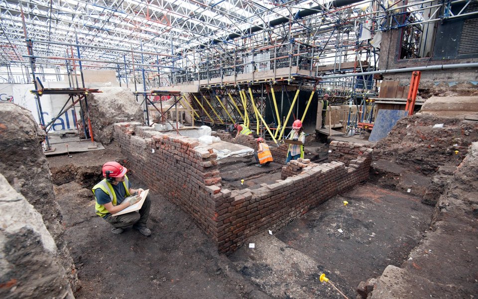 Archaeologists excavating a brick structure.