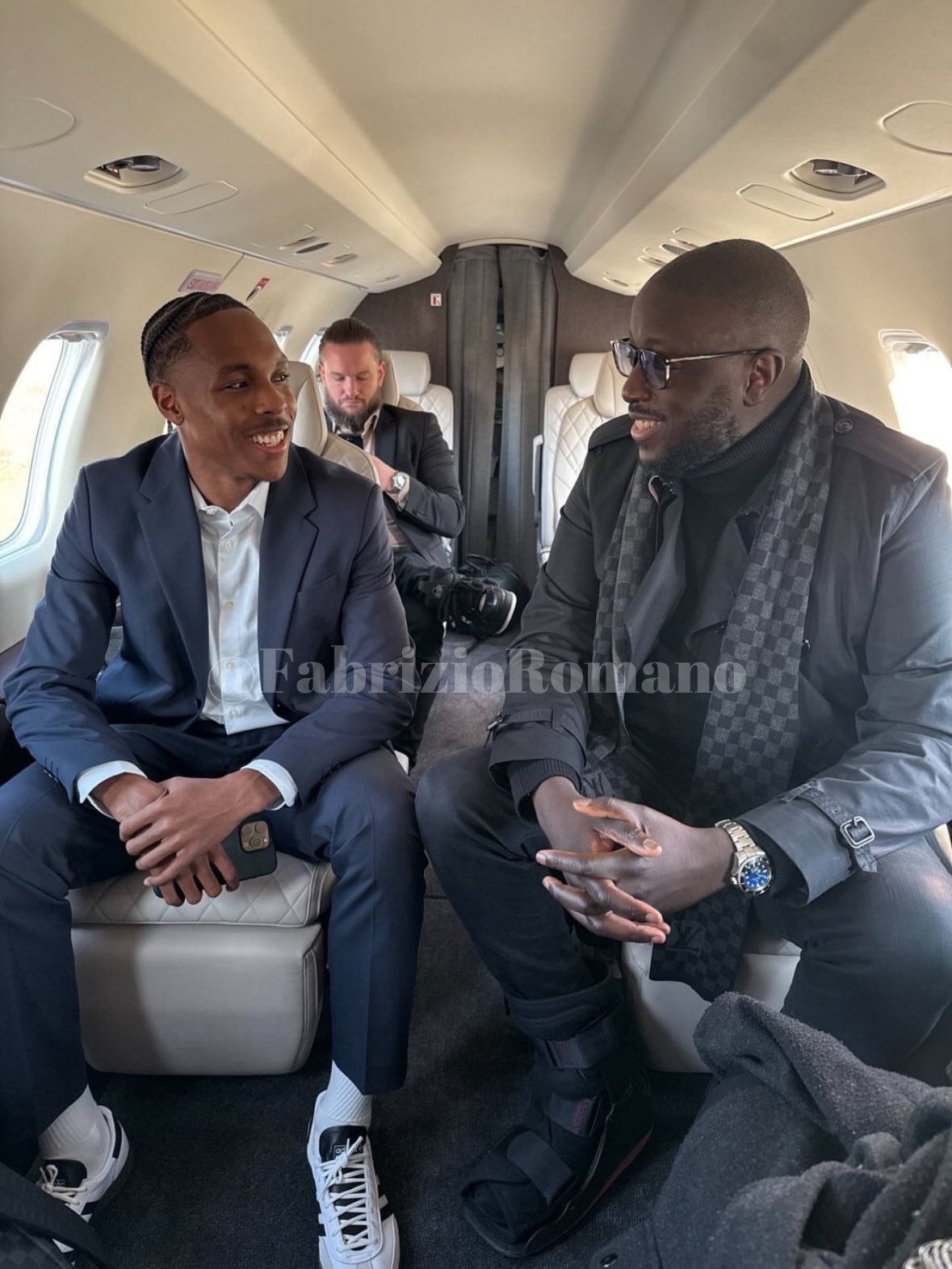 Two men in suits sitting on a private jet.