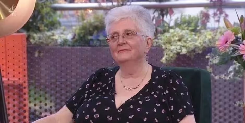 Woman with short gray hair wearing glasses and a black top.