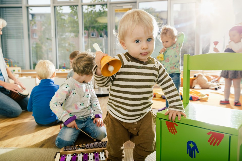 Toddler holding a bell in a preschool classroom.