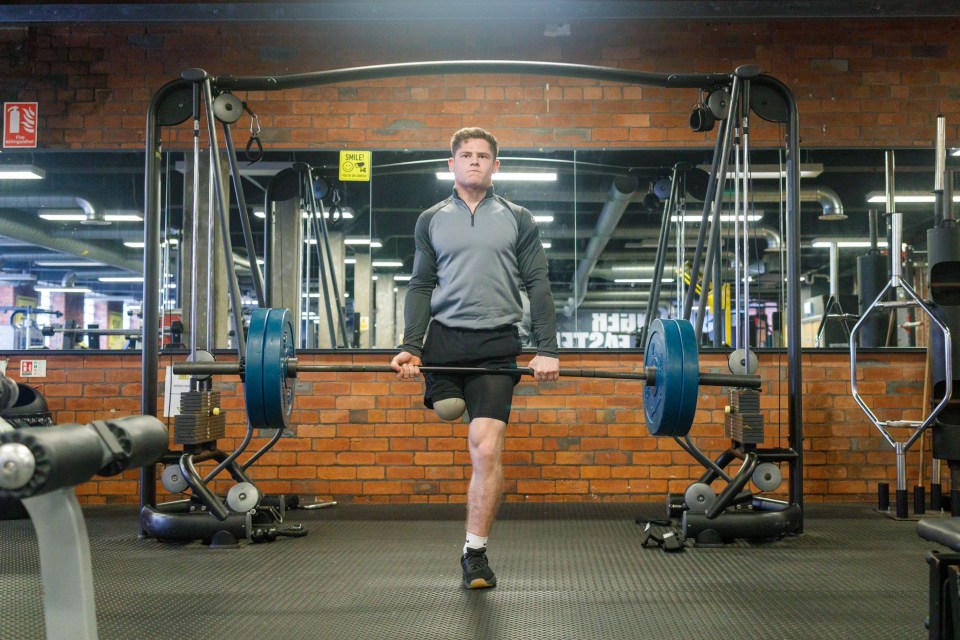 Amputee weightlifter holding a barbell in a gym.