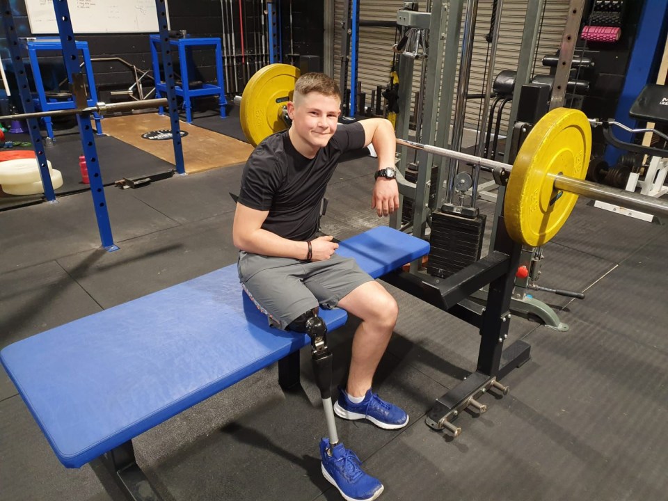 Man with prosthetic leg sitting on weightlifting bench in gym.