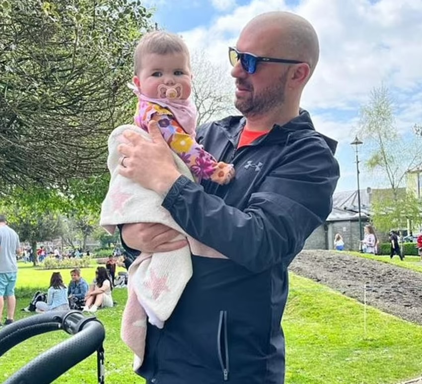 Man holding a baby in a park.