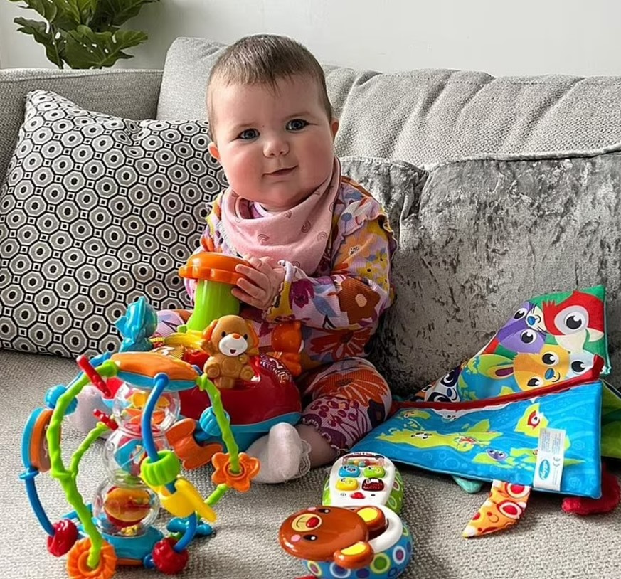 Baby playing with toys on a couch.