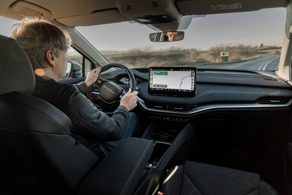 Person driving a Skoda with GPS navigation displayed.