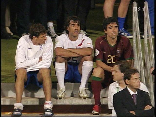 Three soccer players sitting on a bench.