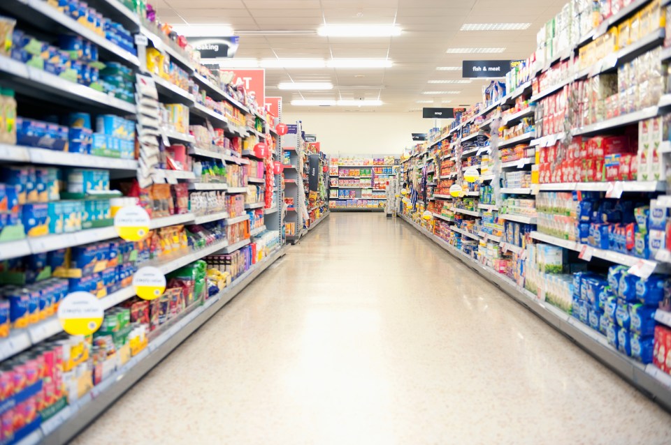 Supermarket aisle with shelves stocked with groceries.