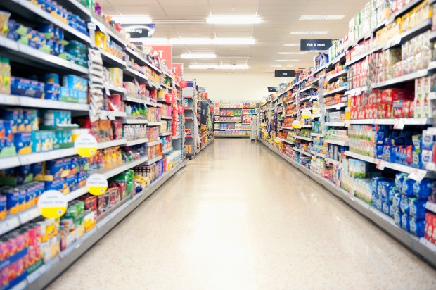 Supermarket aisle with shelves stocked with groceries.