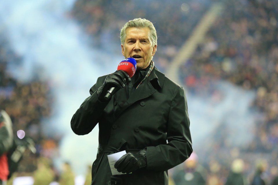 Man in black coat holding a microphone and giving a speech.