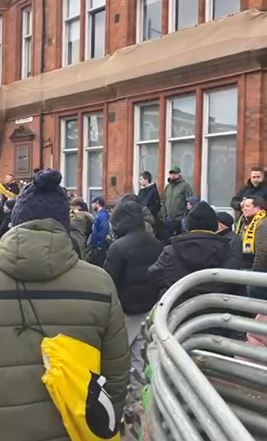 Crowd of people standing outside a brick building.