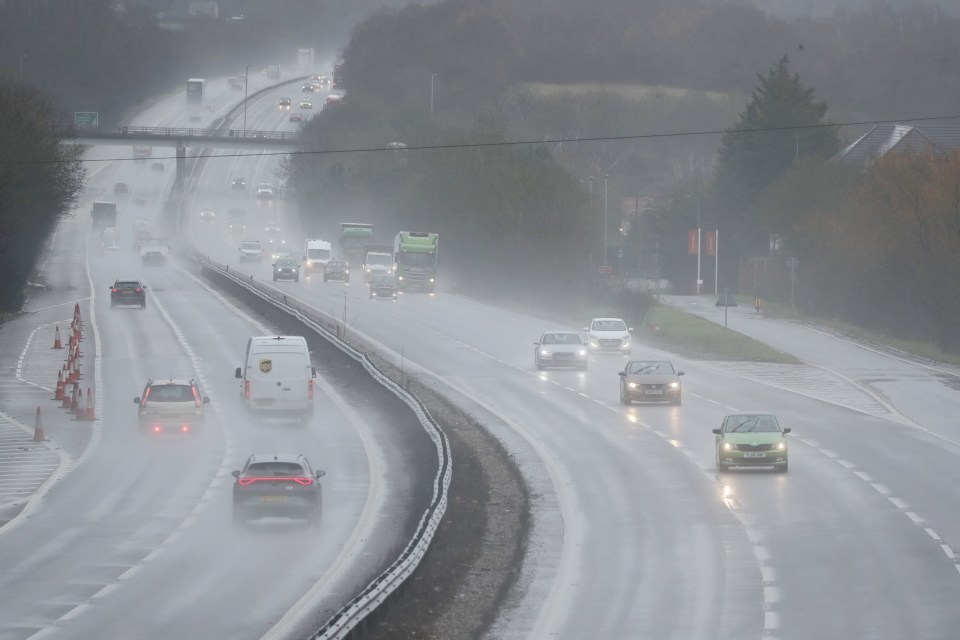 Cars and trucks driving on a highway in heavy rain.