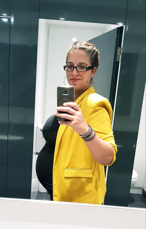 Pregnant woman taking a selfie in a mirror.