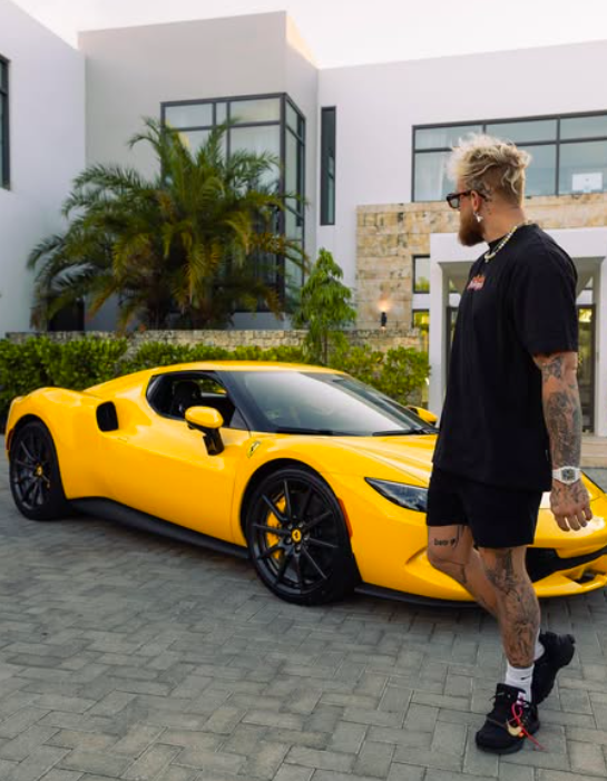 Man standing near yellow sports car in front of house.