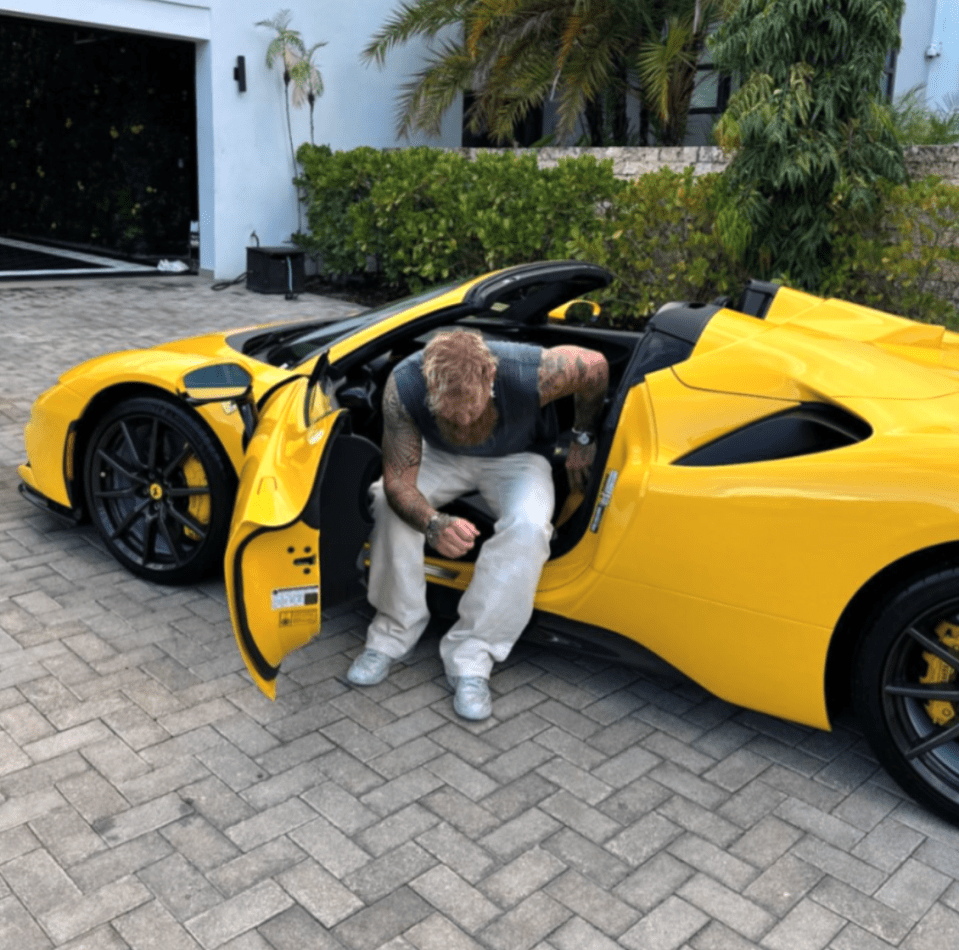 Man crouching beside a yellow convertible sports car.