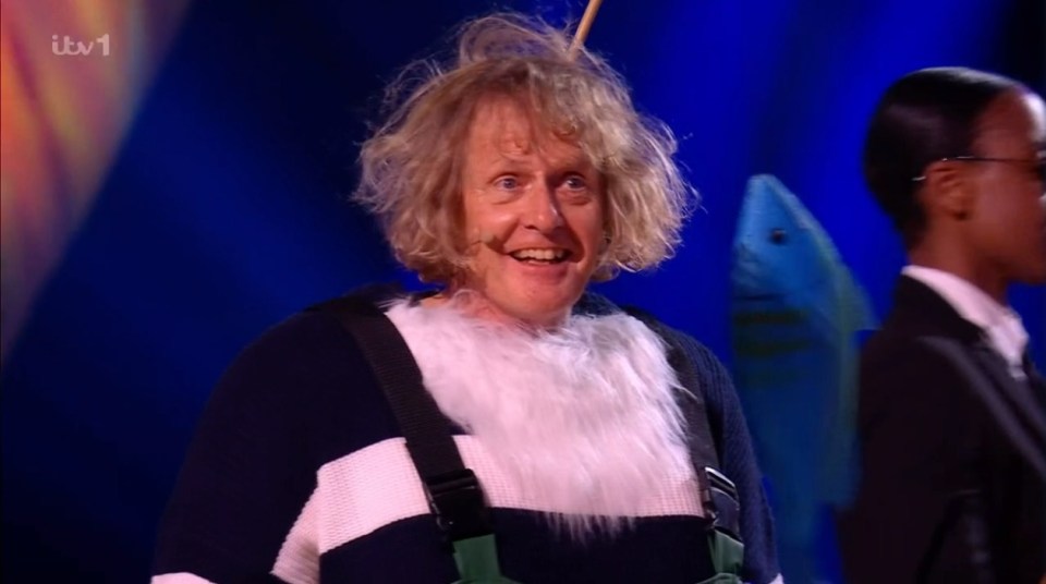 Man in a fisherman costume smiling on stage.