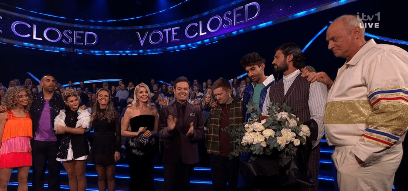 Screenshot of a group of people on a TV show, with a "Vote Closed" sign in the background.