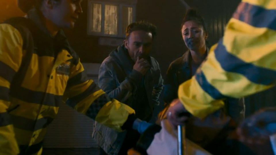 Screenshot of paramedics attending to a distressed couple at night.