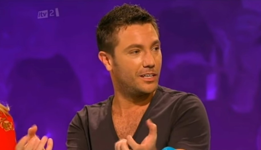 Screenshot of a man speaking on a purple background.