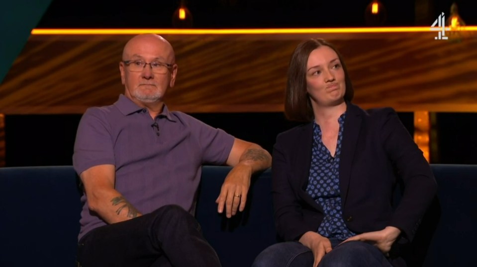 Screenshot of a man and a woman sitting on a couch.