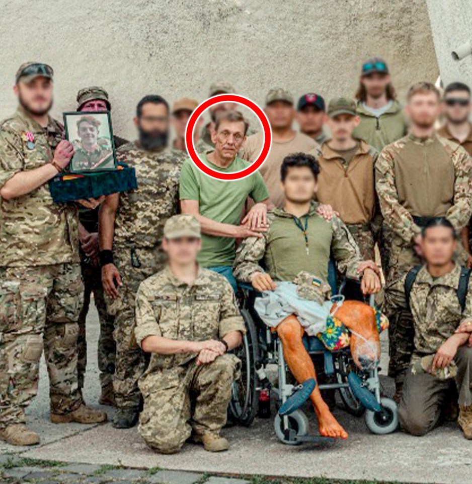 Group photo of soldiers, one in a wheelchair, with a man and a framed photo.