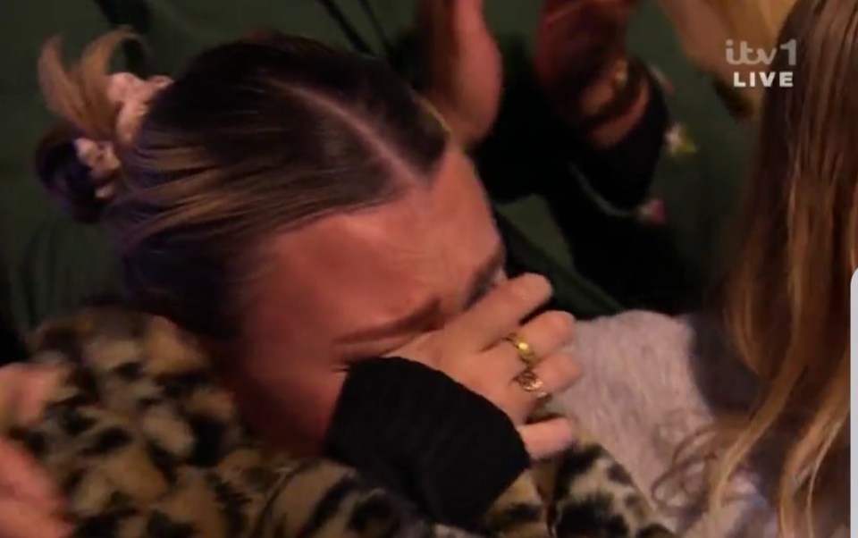 Screenshot of a woman crying and being comforted.