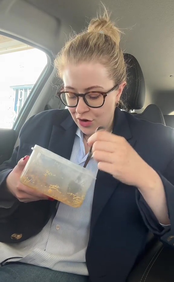 Woman eating from a takeout container in a car.