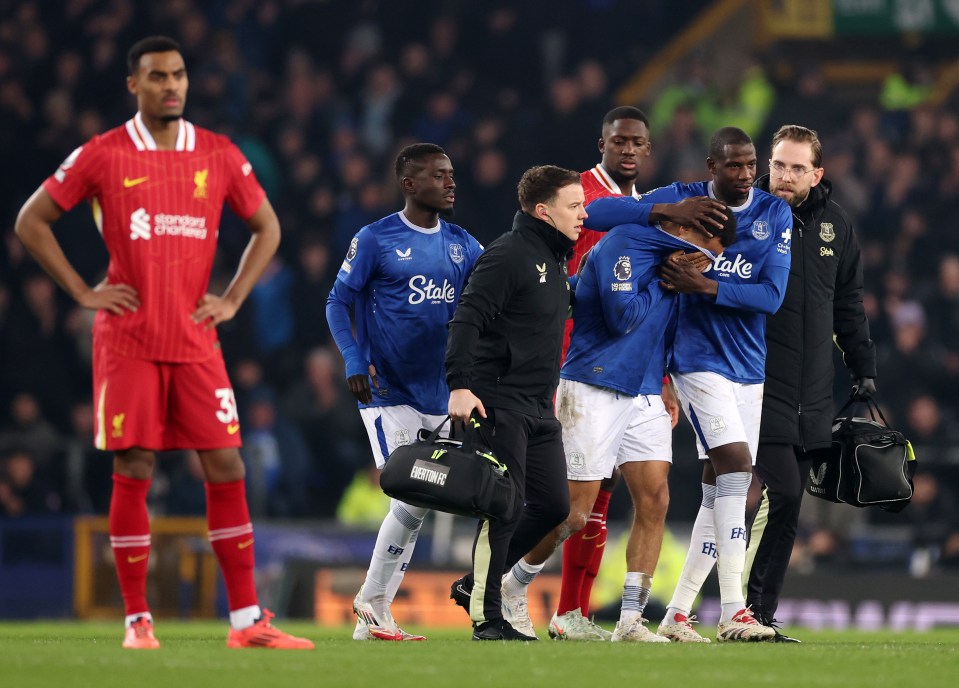 Everton player being consoled and assisted off the pitch after an injury.