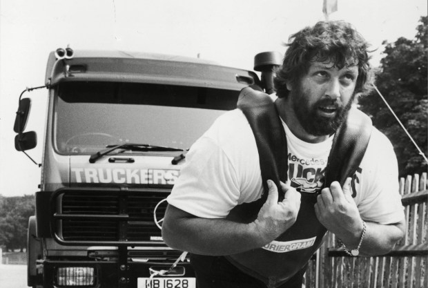 a man is carrying a weight in front of a truck that says truckers