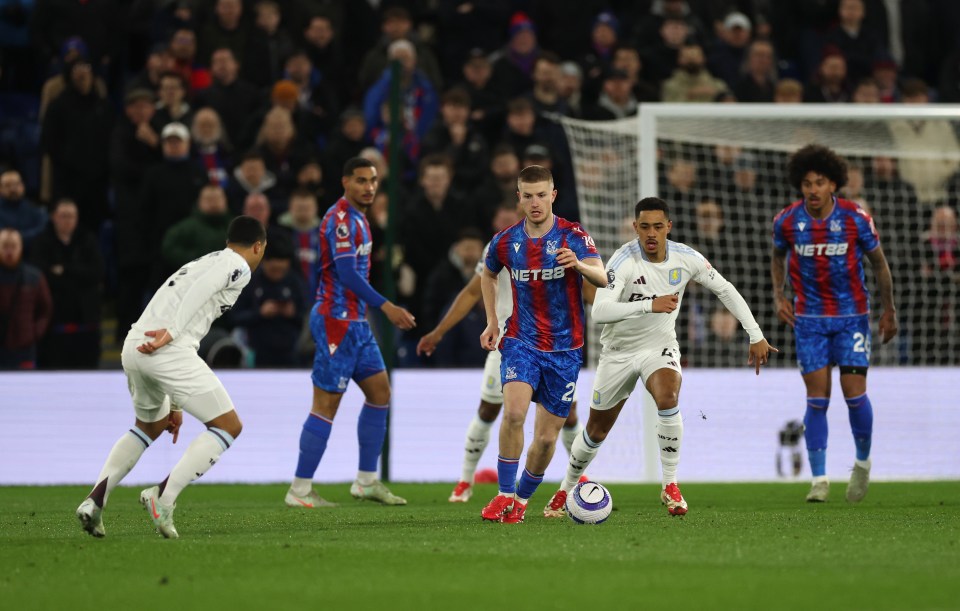 A soccer player dribbling the ball during a Crystal Palace vs Aston Villa game.