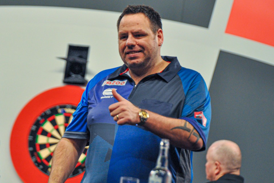 Adrian Lewis giving a thumbs-up at a darts championship.