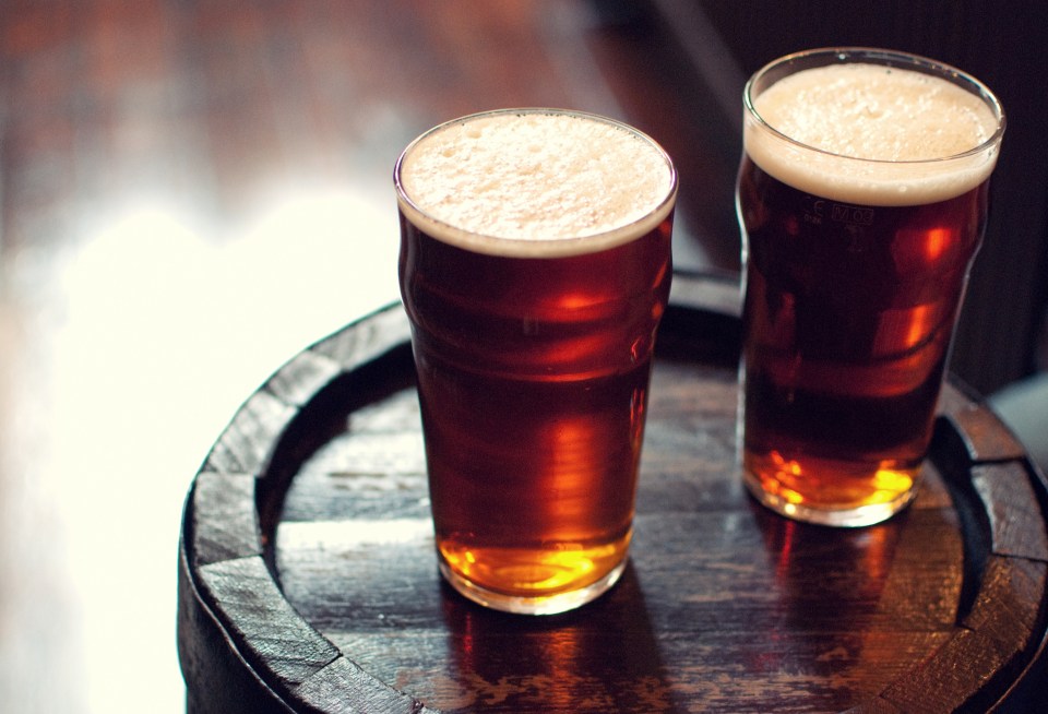 Two pints of bitter ale on a wooden barrel.