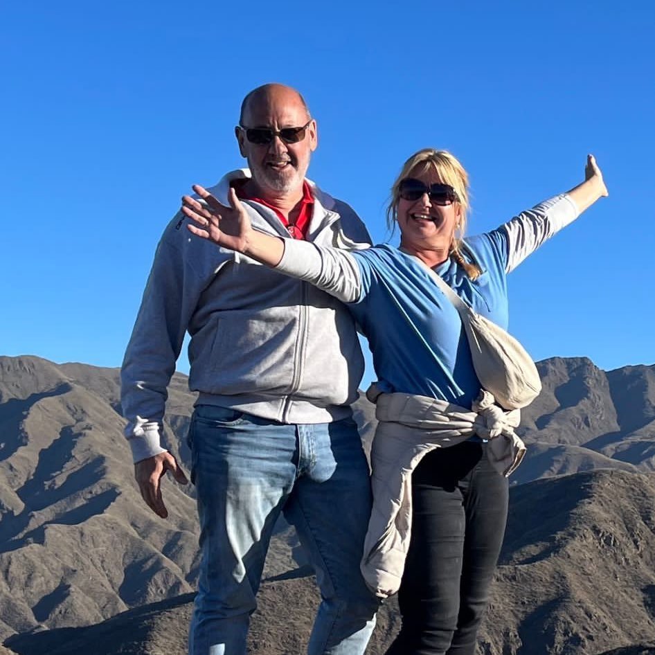 Andrew and Dawn Searle posing for a photo in front of mountains.