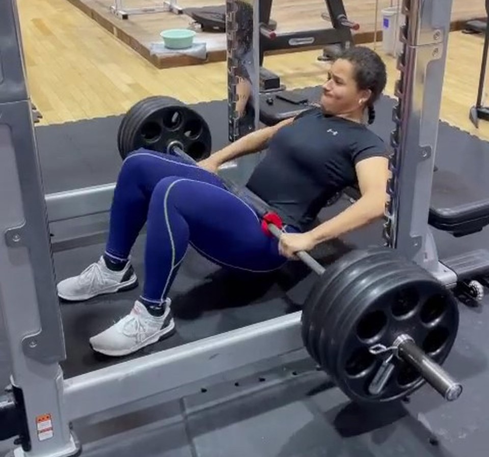 Woman performing barbell hip thrusts in a gym.