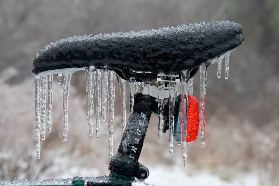 Bicycle seat covered in ice during an ice storm.