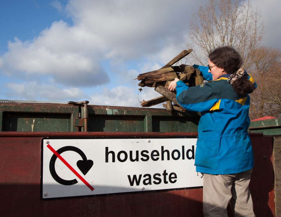 Woman throwing rotten wood into a household waste skip.