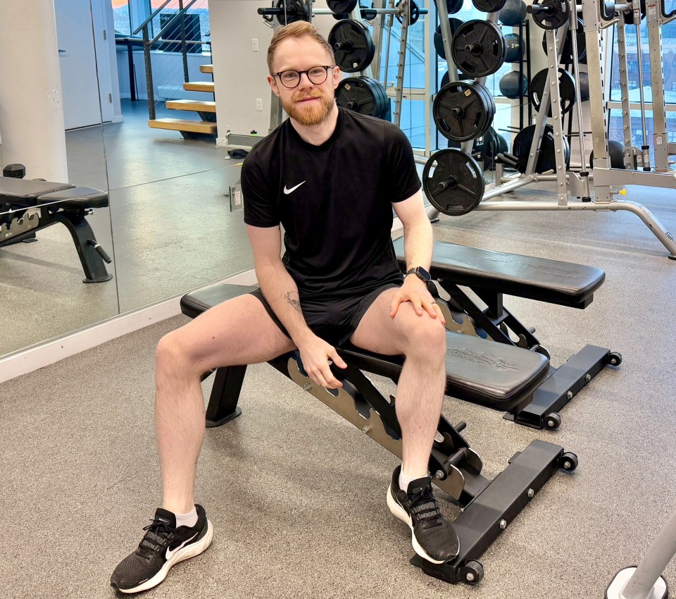 Man sitting on a weight bench in a gym.