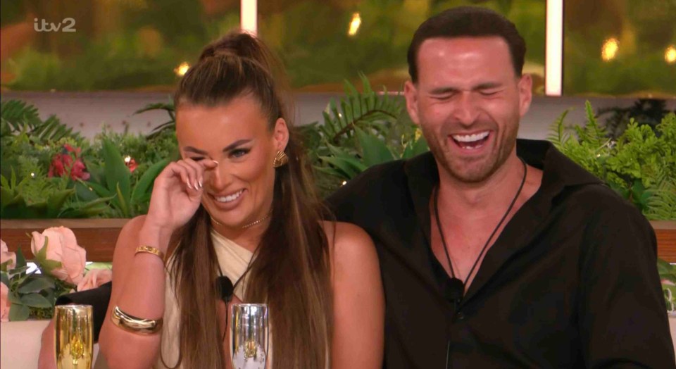 A woman cries while a man laughs at a Love Island dinner party.